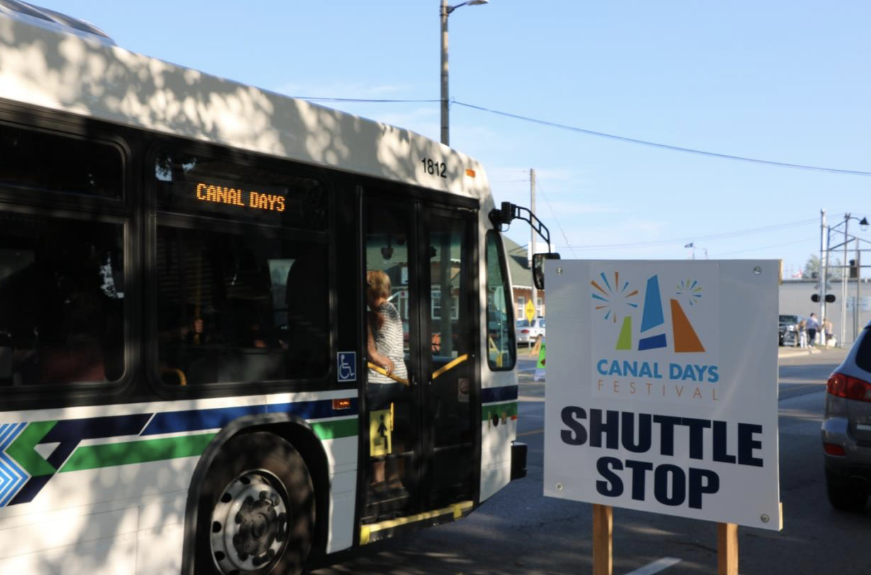 Canal Days Shuttle City bus beside a Canal Days shuttle stop sign