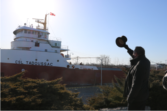 Mayor Bill Steele holding a top hat looking at a boat going through the canal