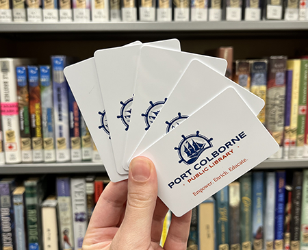 Library cards held in front of a shelf of books