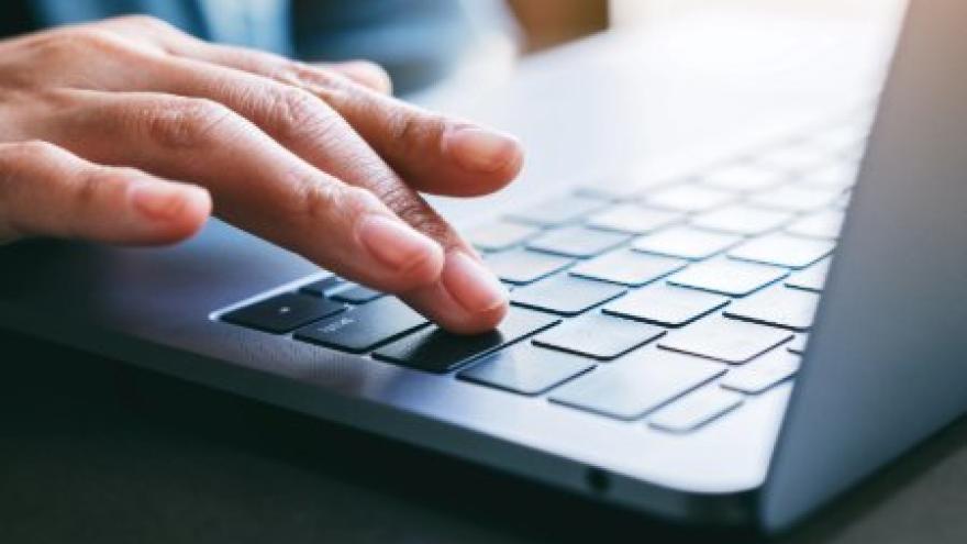 A close-up of a hand typing on a laptop keyboard.