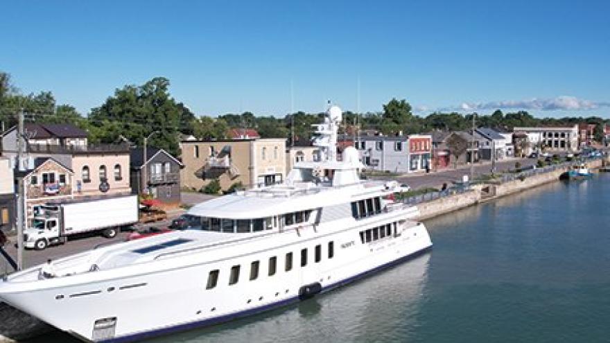 Luxury yacht docked in a calm waterway beside a quaint riverside town.