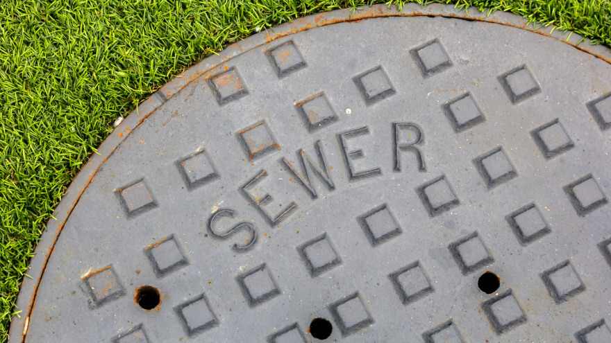 Round sewer manhole cover on green grass.