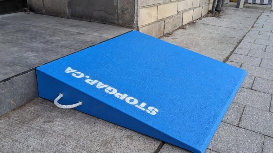 Bright blue accessibility ramp positioned against a stone building's entrance.