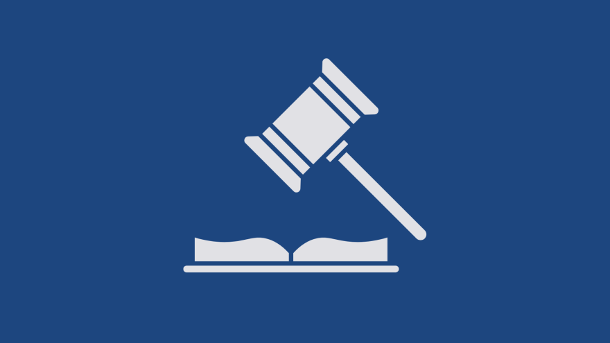 A white gavel resting on a book against a blue background.
