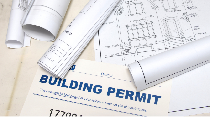 Blueprints and a building permit are arranged on a flat surface.