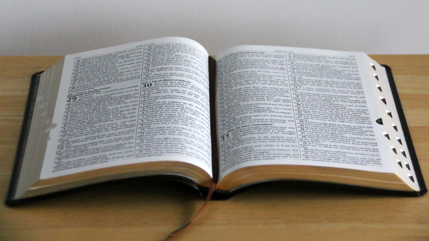 Open book lying on a wooden table, displaying pages filled with text.