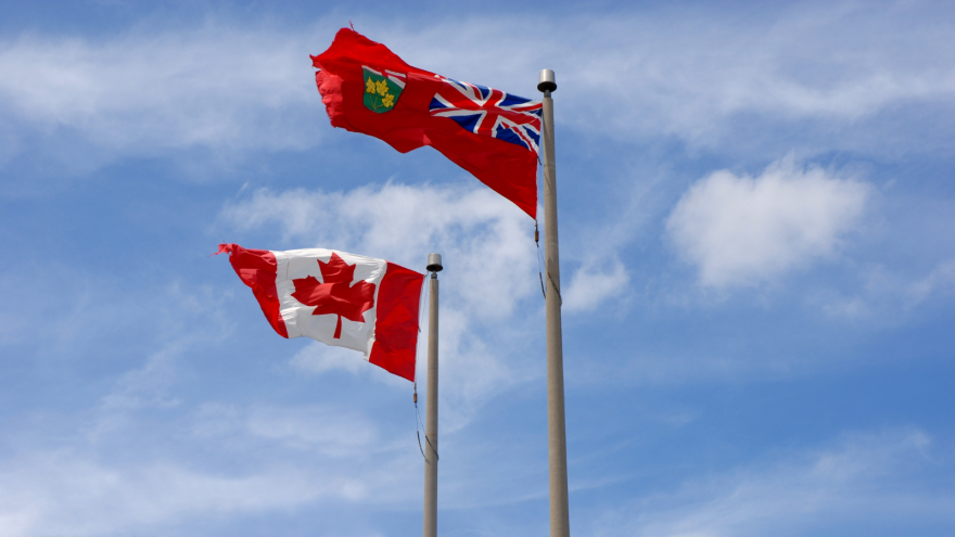 Three flags waving on poles against a bright blue sky.