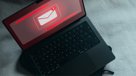 Laptop on a soft surface displaying a red alert about a suspicious email.