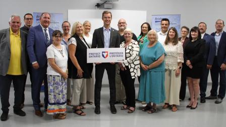 A diverse group of people standing together, holding a sign in a well-lit indoor setting.