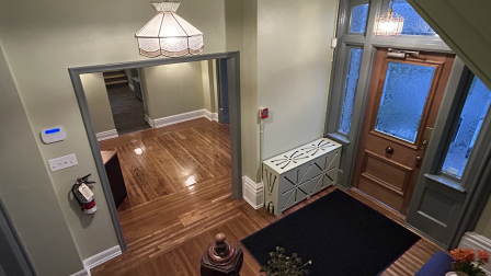 View of a warmly lit entryway with wooden flooring, decorative plants, and vintage light fixtures.