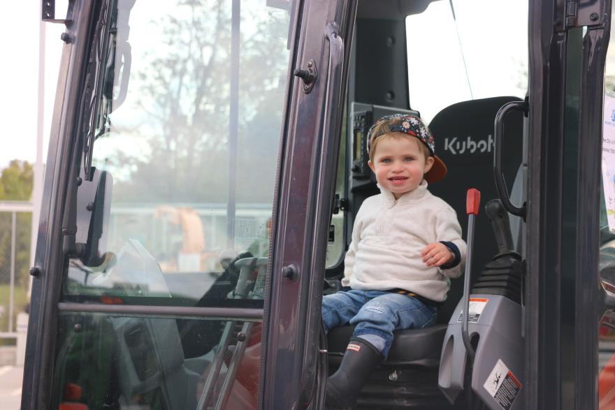 A child sitting in the driver's seat of a construction vehicle.