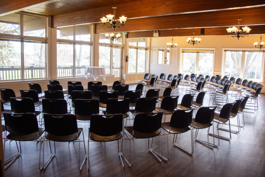 Rows of black chairs set up in a well-lit room with large windows.