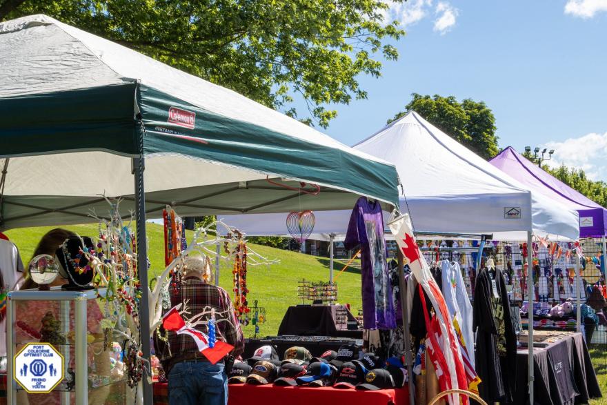 Vibrant market stalls with various crafts and goods under sunny skies.