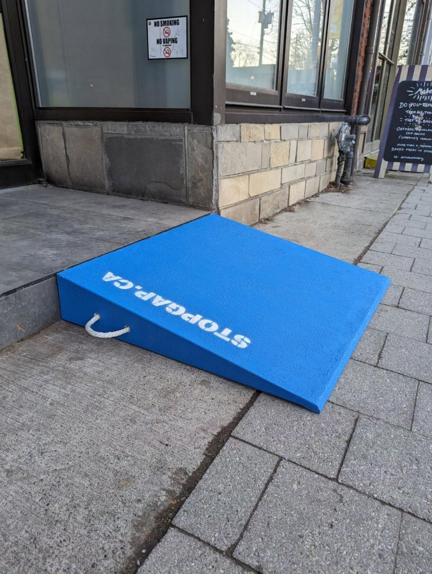 Bright blue accessibility ramp positioned against a stone building's entrance.