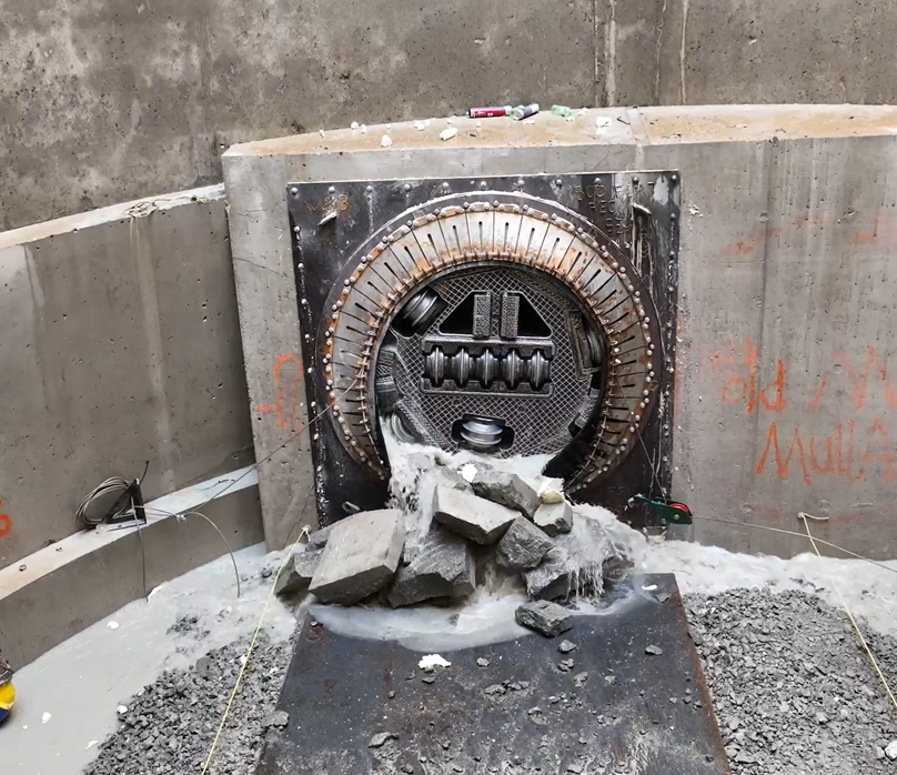 A circular metal door surrounded by rocks in a concrete structure.