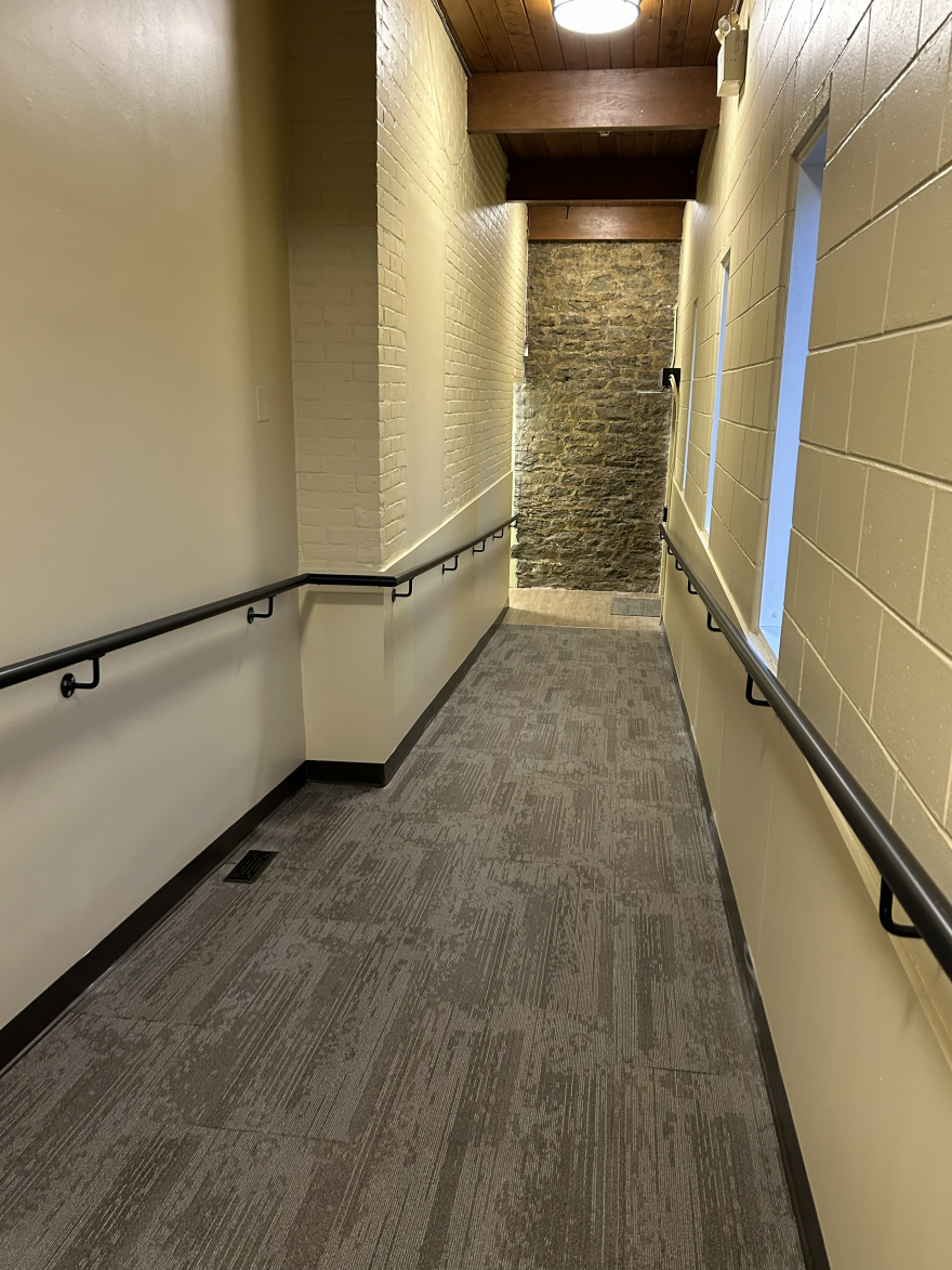 Narrow hallway with textured walls, a stone feature, and two windows.