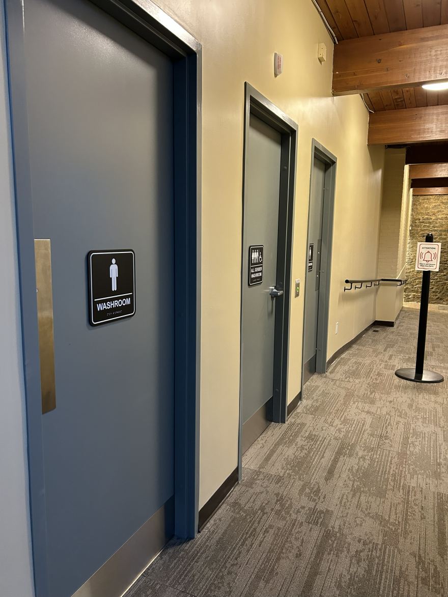 Two restroom doors in a hallway, one marked for men, the other for all genders.