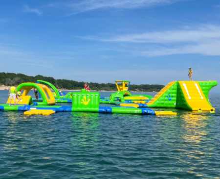 Brightly coloured inflatable water park with slides and obstacles on a lake.