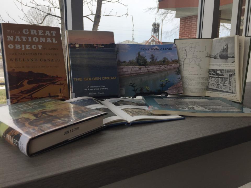 A collection of books stacked on a table near a window, showcasing various covers and illustrations.