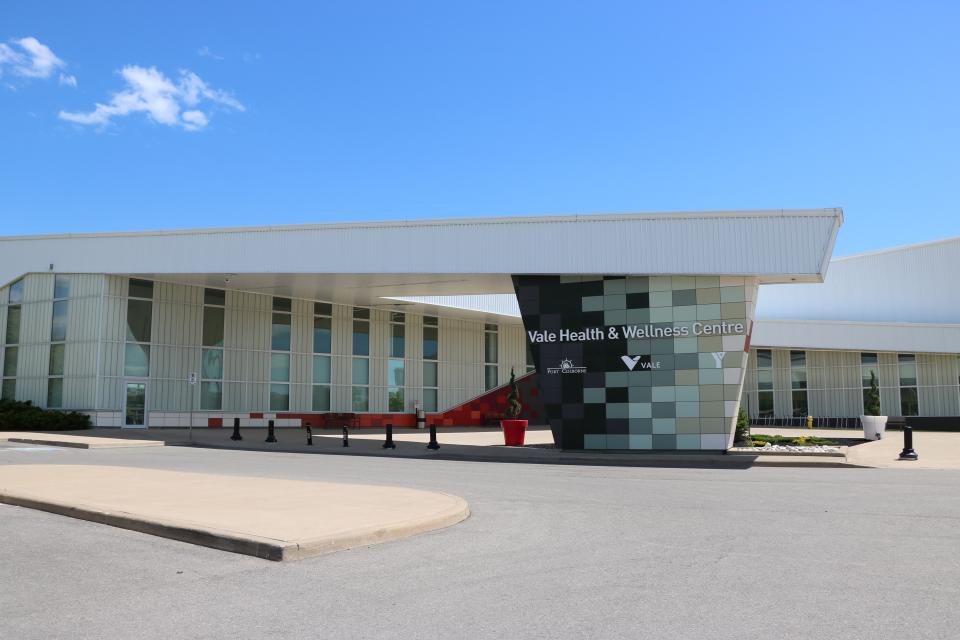 Modern building with a glass façade and patterned stone entrance, under a blue sky.
