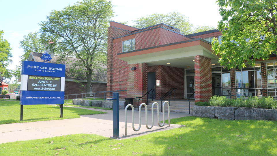 Community centre with a brick façade, bike racks, and green lawn in bright sunlight.