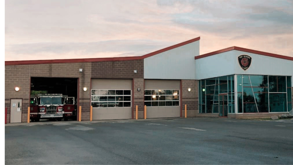 Fire station exterior with two garage doors and a glass entrance at sunset.