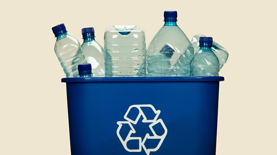 A blue recycling bin filled with various plastic water bottles.