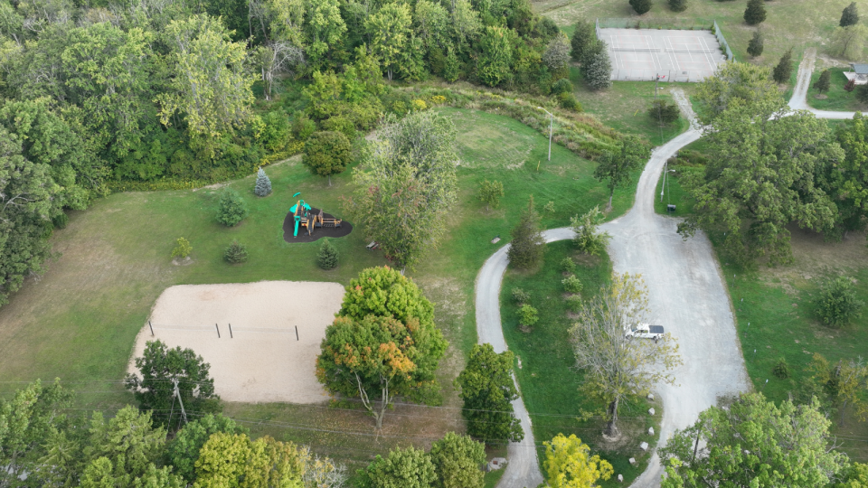 Aerial view of a park featuring a sandy area, trees, and a winding pathway.