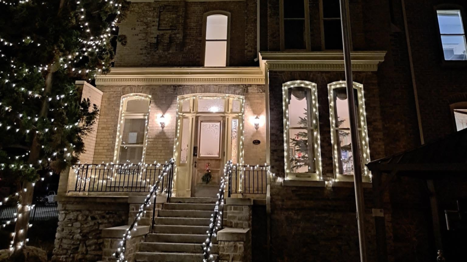 Historic building decorated with festive lights, featuring a welcoming entrance and stairs.