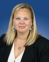 Professional headshot with a person in formal attire and a blue background.