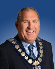 Person smiling confidently, wearing a medal chain, with a blue background.