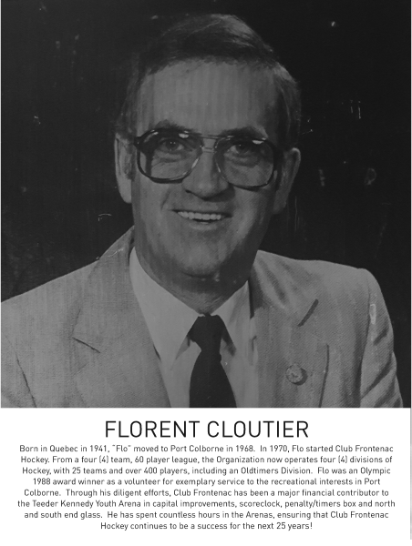 Black and white portrait of a smiling individual wearing glasses and a suit.