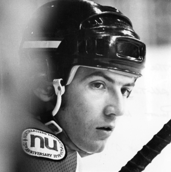 Close-up of a hockey player wearing a helmet, focused and serious expression. Black and white photo.