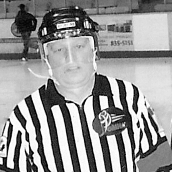 Black and white photograph of a hockey referee wearing a striped jersey and helmet.