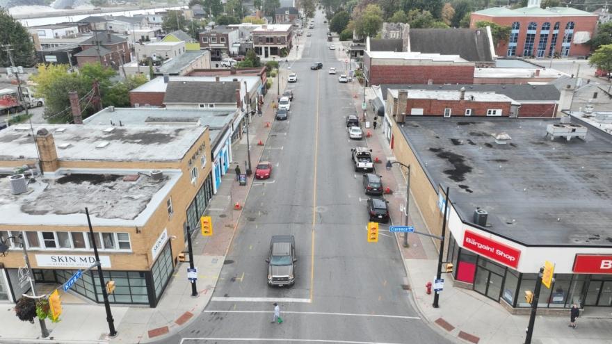 Aerial view of a quiet street with shops on either side and a vehicle in motion.