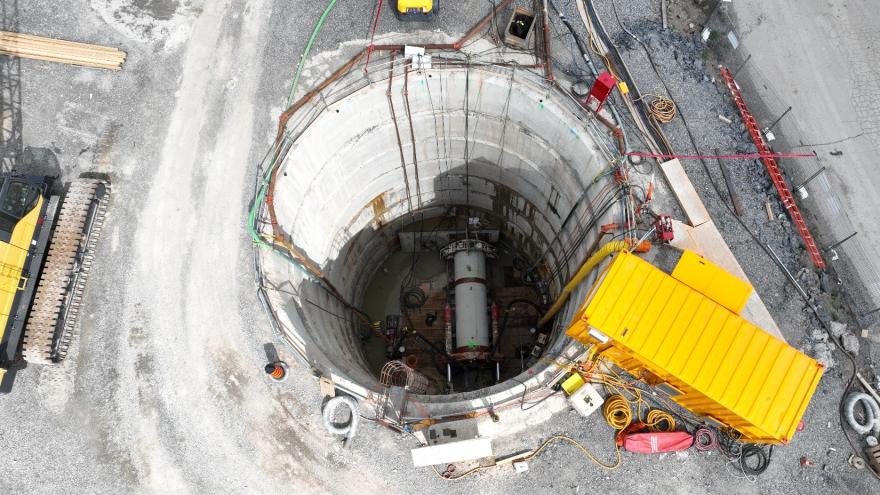 Aerial view of a large construction site with a deep circular excavation and machinery.