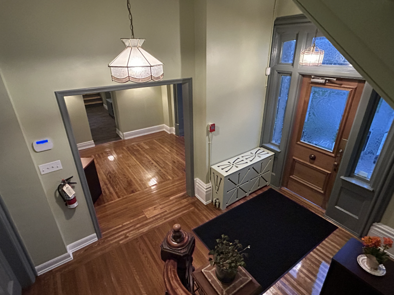 View of a warmly lit entryway with wooden flooring, decorative plants, and vintage light fixtures.